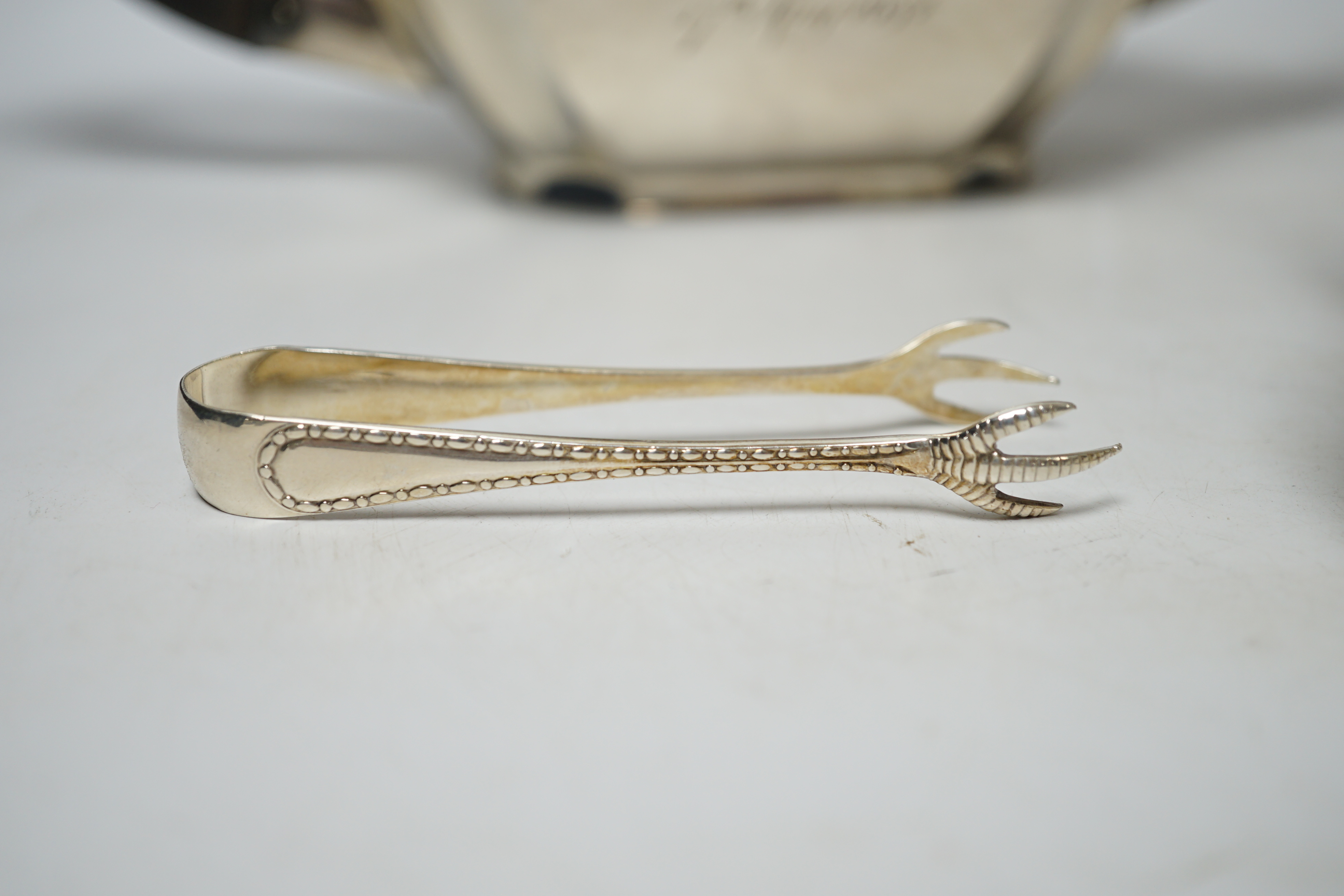 A George V three piece silver tea set by Robert Pringle & Sons, London, 1933, with engraved inscription, together with a pair of associated silver sugar tongs, gross weight 40.7oz.